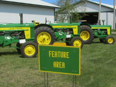 John Deere 620, 720, and 820 Standard tractors on display in the feature area.