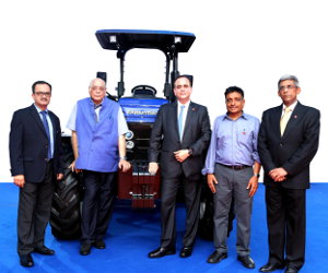 Escorts personnel pose in front of a model in their new global tractor line.